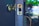 A close-up view of a door with a brass doorknob and a latch plate. The latch plate is engraved with the brand name Kwikset. The background is softly blurred with hints of greenery and light, suggesting an outdoor setting.