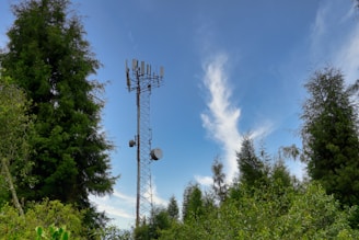 A modern communication tower surrounded by green energy solar panels under a clear blue sky