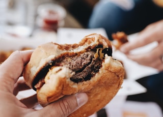 person holding burger with patty