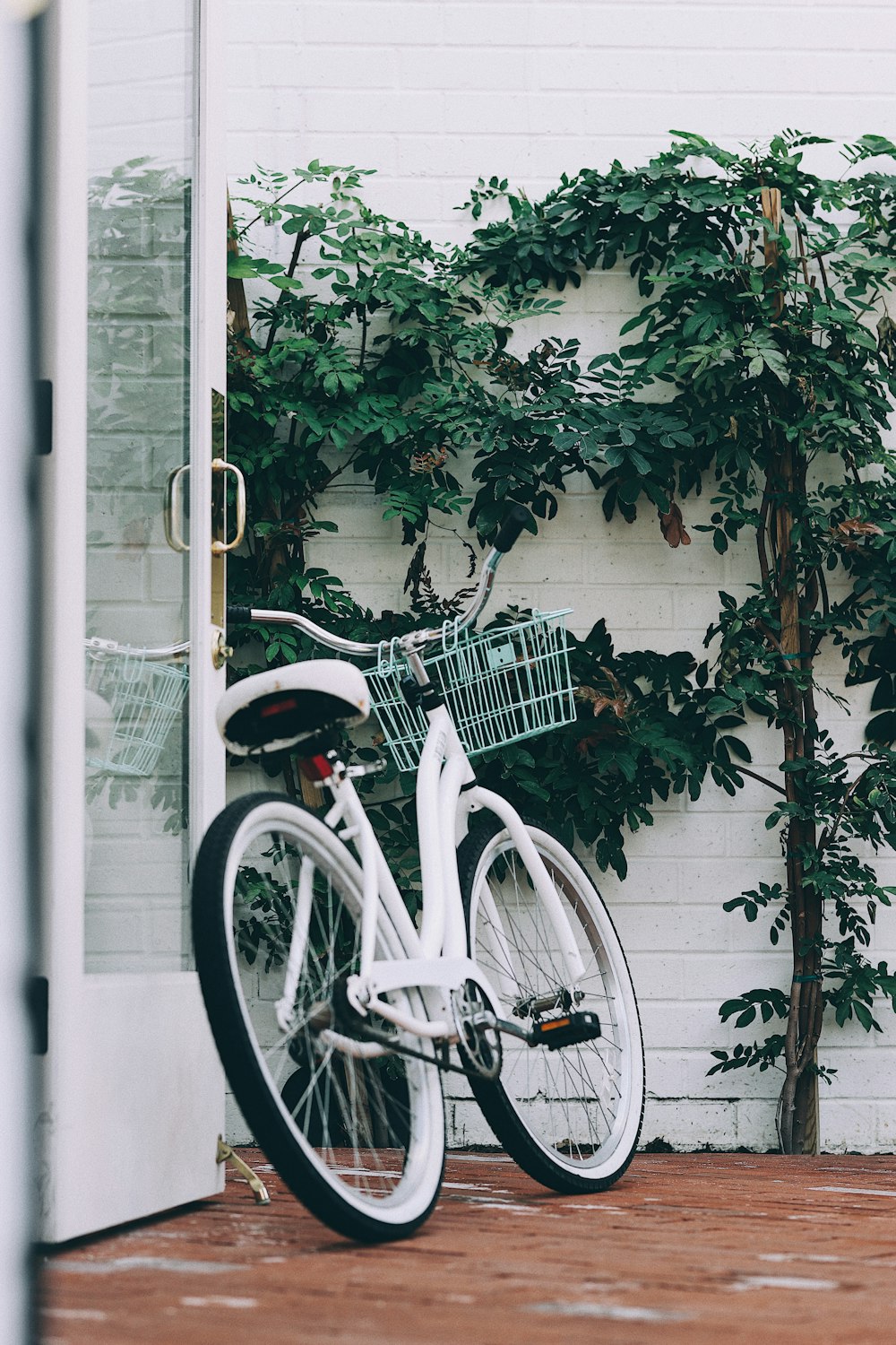 white and red bicycle parked beside white metal fence