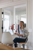A focused virtual assistant working on a laptop in a modern office space.