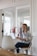 Portrait of a confident woman smiling while working on a laptop in a cozy, modern workspace.