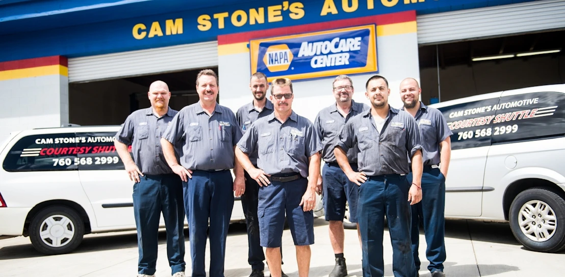 Two brothers in work uniforms smiling confidently in front of their Fraterfix service van.