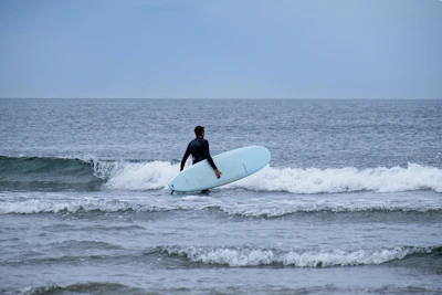 An instructor helping a beginner adjust their wetsuit before heading into the waves.