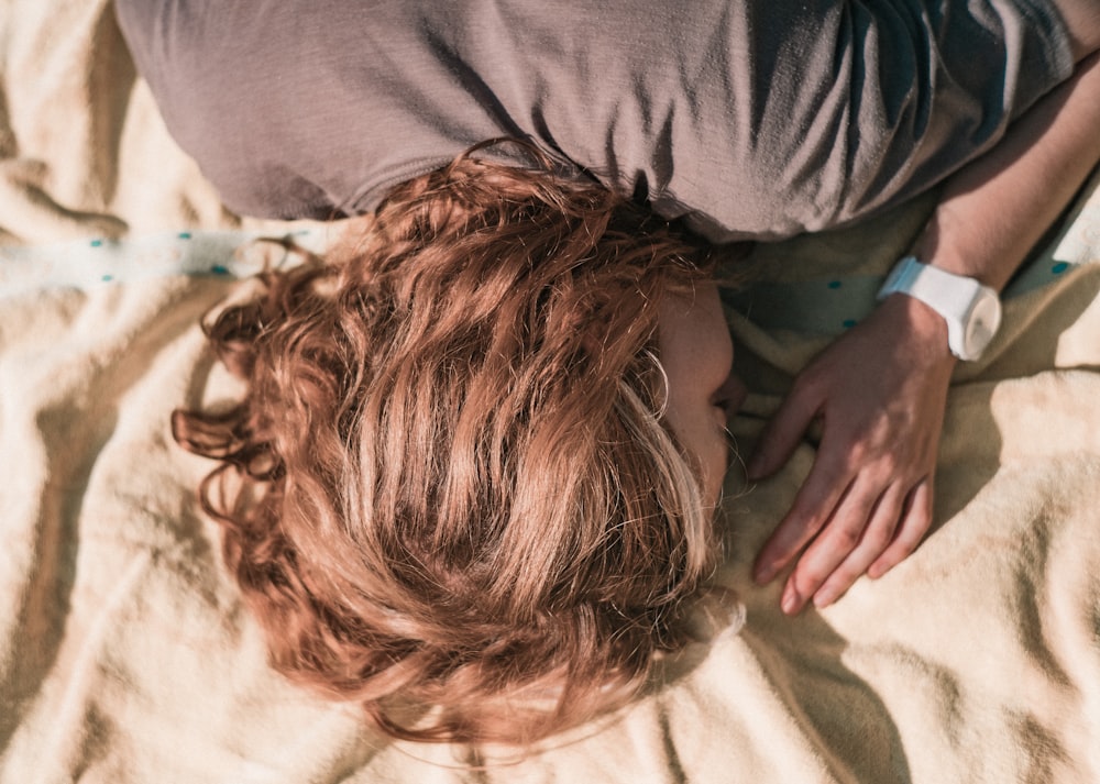 Mujer con camisa gris de manga larga acostada en la cama