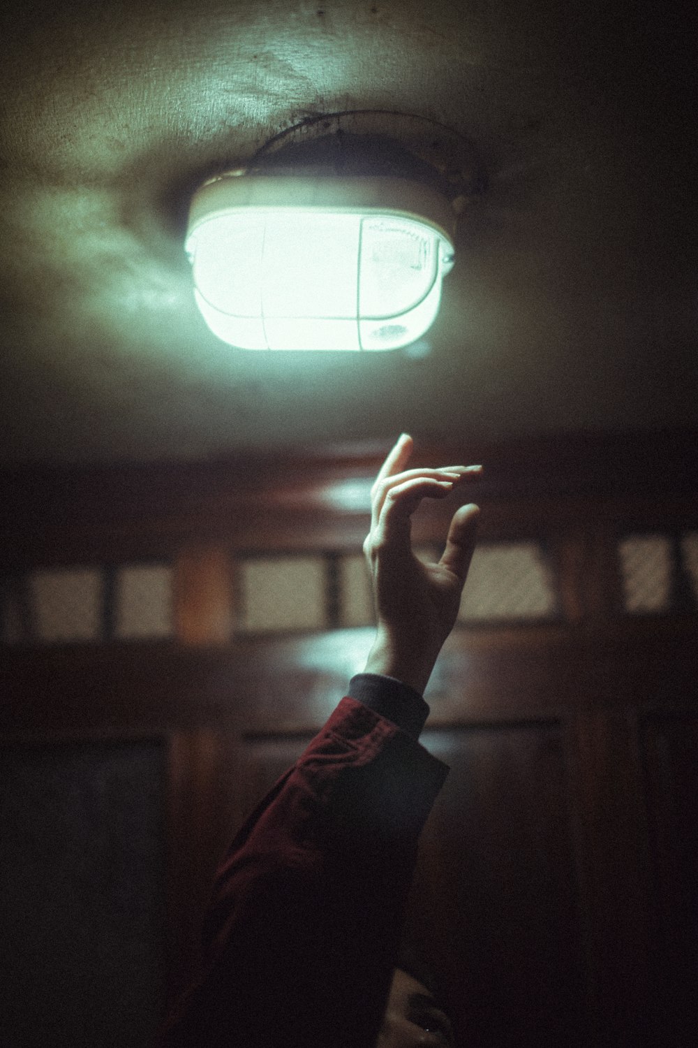 person in red long sleeve shirt holding white round light