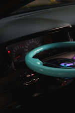 Close-up of a technician using an OBD2 scanner on a sleek black car dashboard illuminated with blue accents.