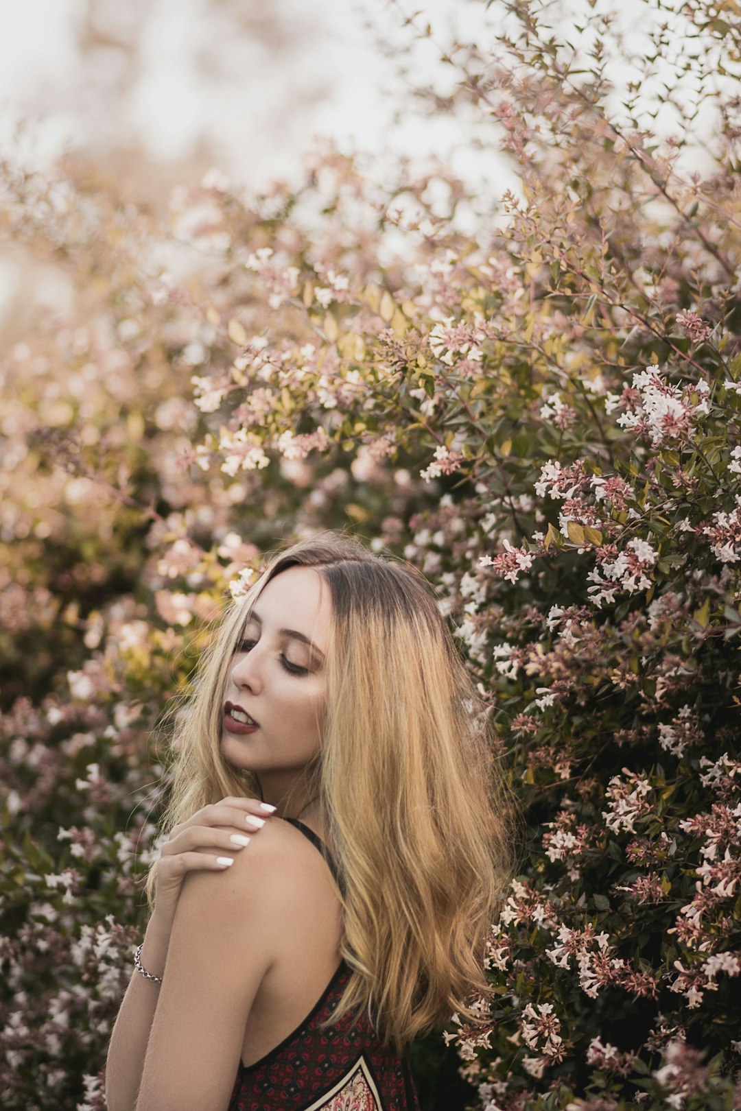 woman in black tank top standing beside yellow flowers during daytime