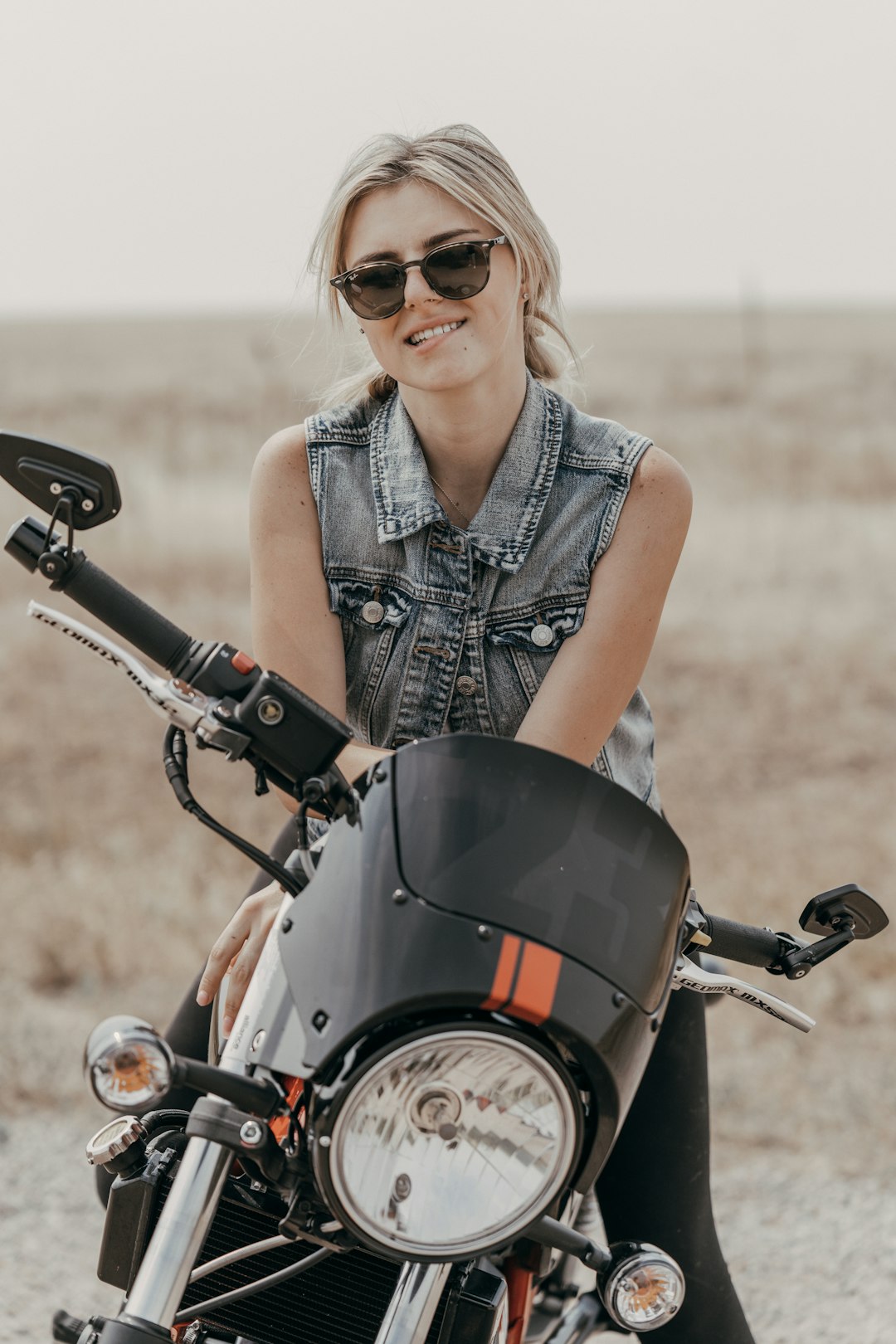 woman in blue denim vest riding on motorcycle during daytime
