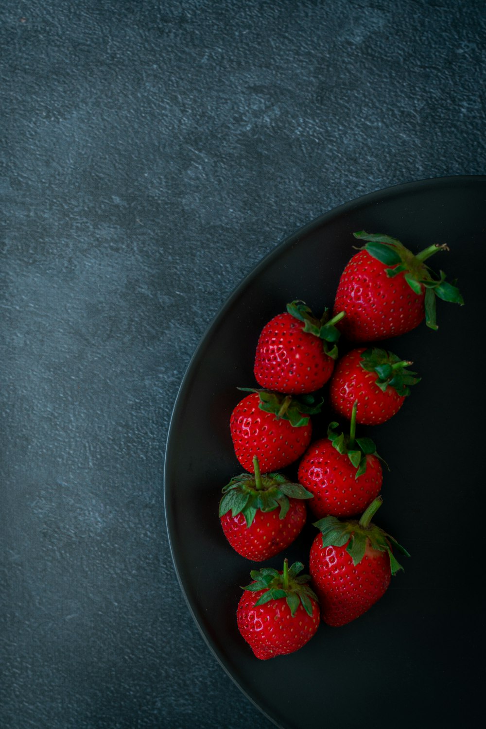 red strawberries on black ceramic bowl
