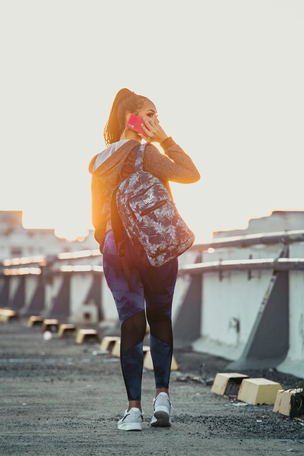 woman in orange and white floral shirt and black pants standing on gray concrete floor during