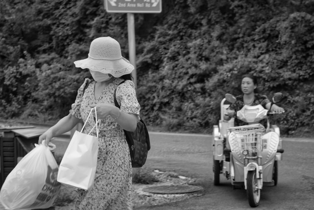woman in black and white dress with white hat standing beside black and white bicycle