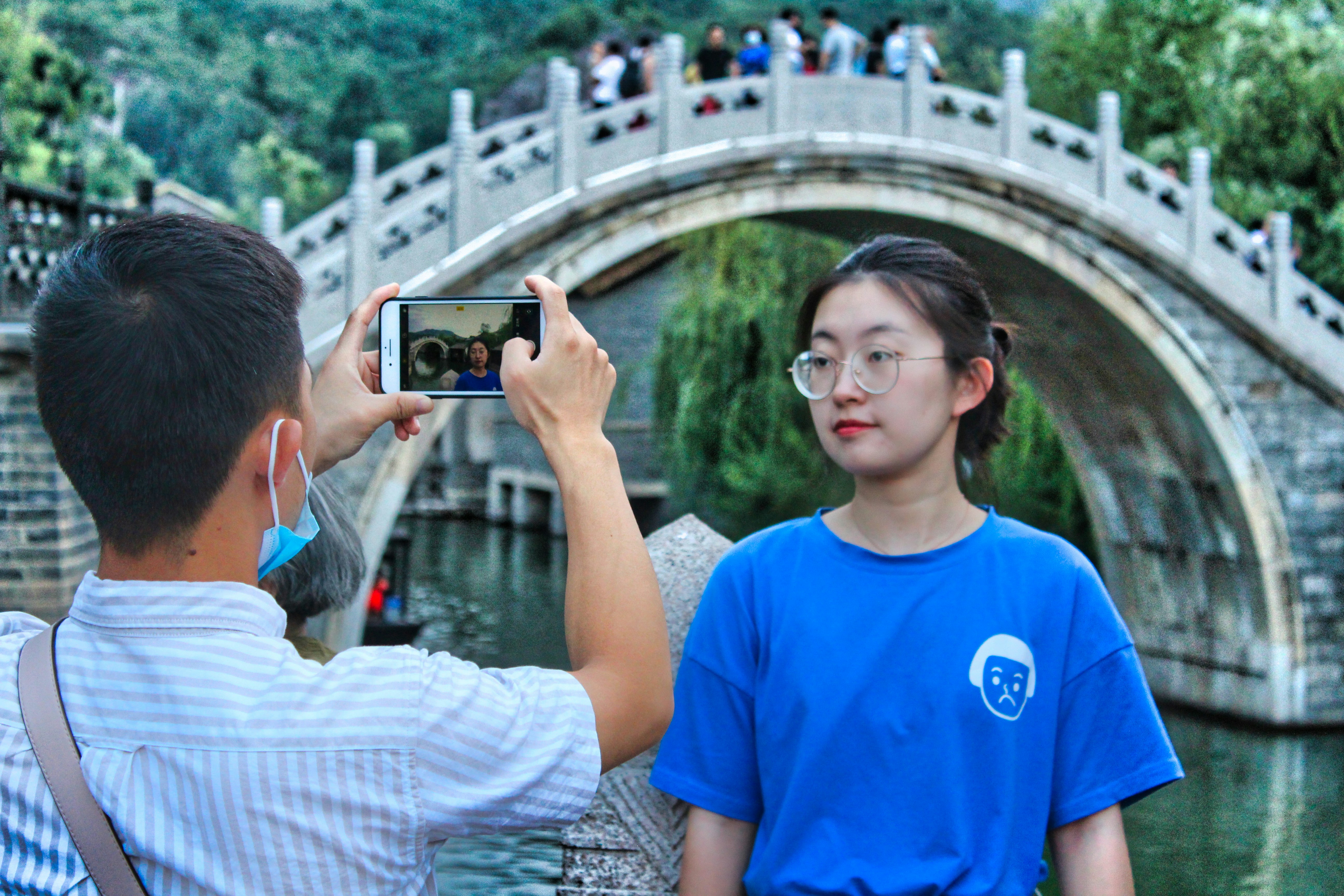man in blue crew neck t-shirt holding black smartphone