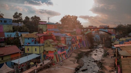 blue red and white concrete building near green trees under white clouds during daytime in Malang Indonesia