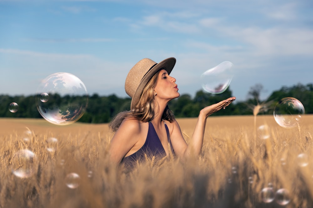 woman in brown sun hat and black tank top sitting on brown grass field during daytime