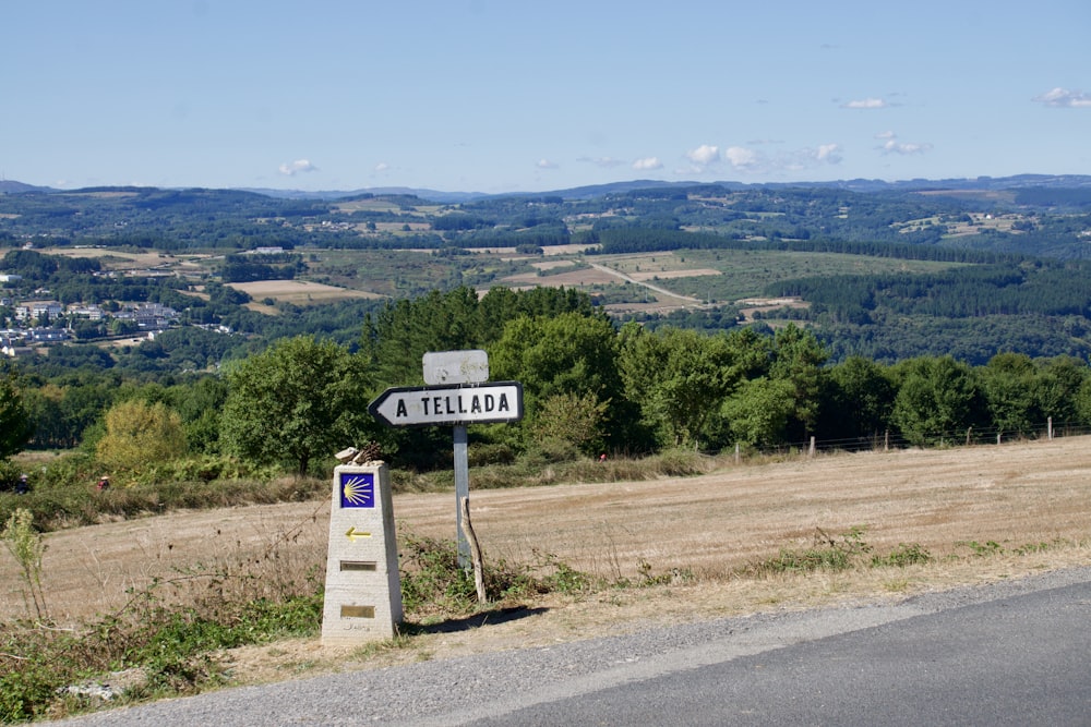 white and black road sign near green grass field during daytime