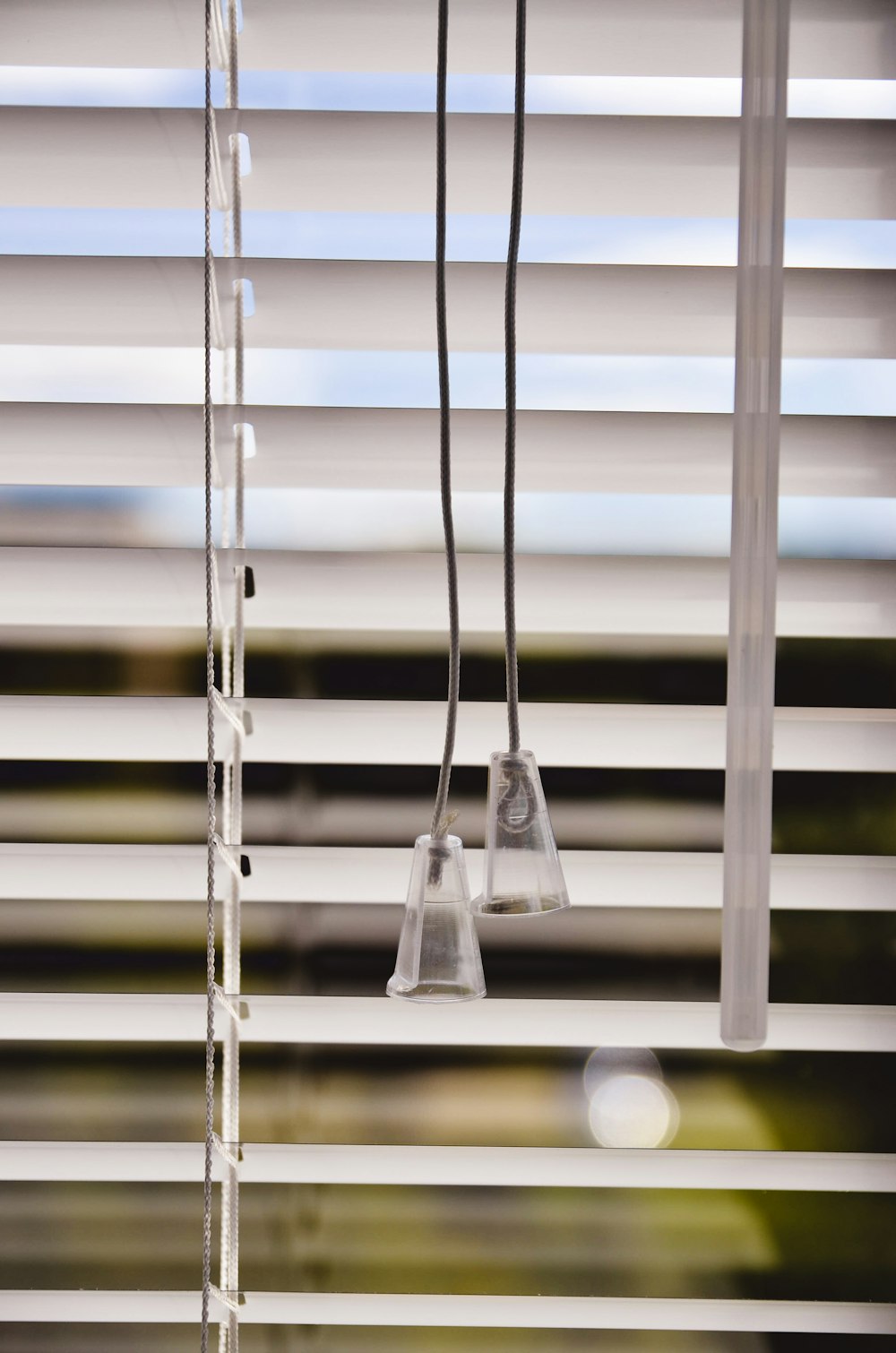 white wooden window blinds with hanging clear glass pendant lamps