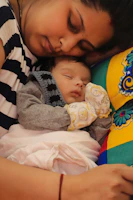 A mother resting peacefully with her baby nestled close, both surrounded by calming pastel colors.