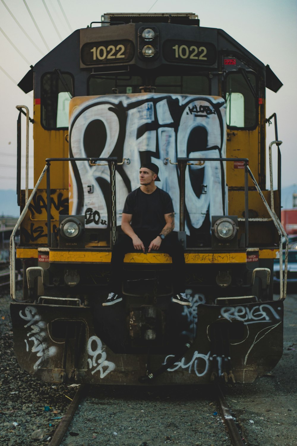 man in yellow shirt and black pants standing beside train