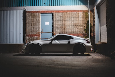 A sleek vehicle wrapped in bright vinyl parked in an urban industrial setting.