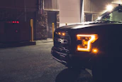 Modern tow truck parked in front of the company headquarters with subtle golden lighting.