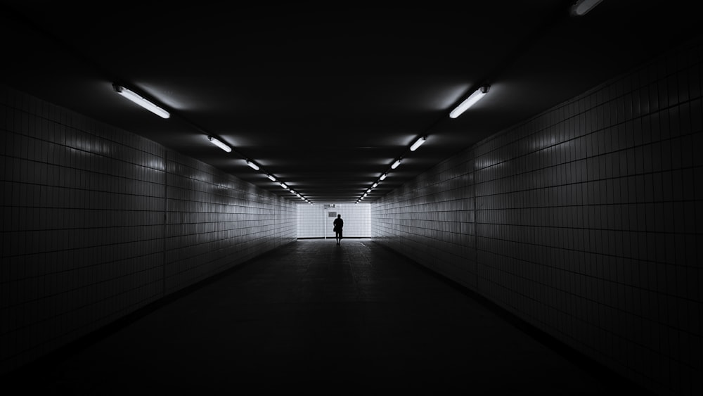 흰 셔츠를 입은 사람이 터널을 걷고 있다