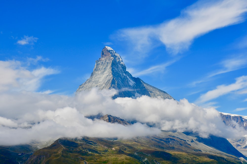 a very tall mountain surrounded by clouds in the sky