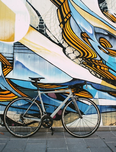 blue city bike parked beside white blue and brown wall