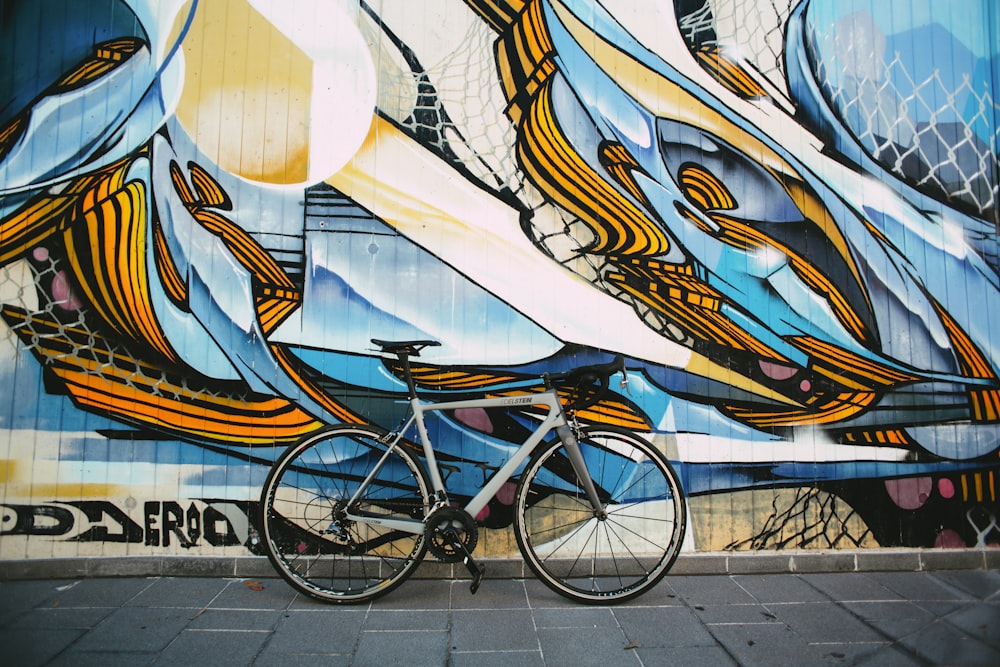 Bicicleta urbana azul estacionada junto a la pared blanca, azul y marrón