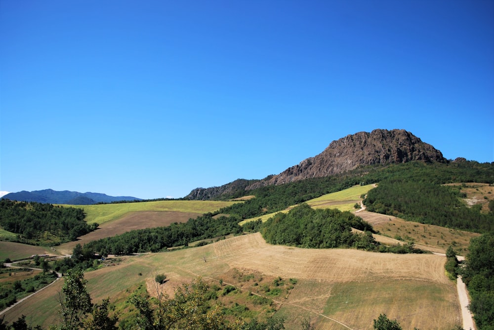 green grass field and mountain under blue sky during daytime