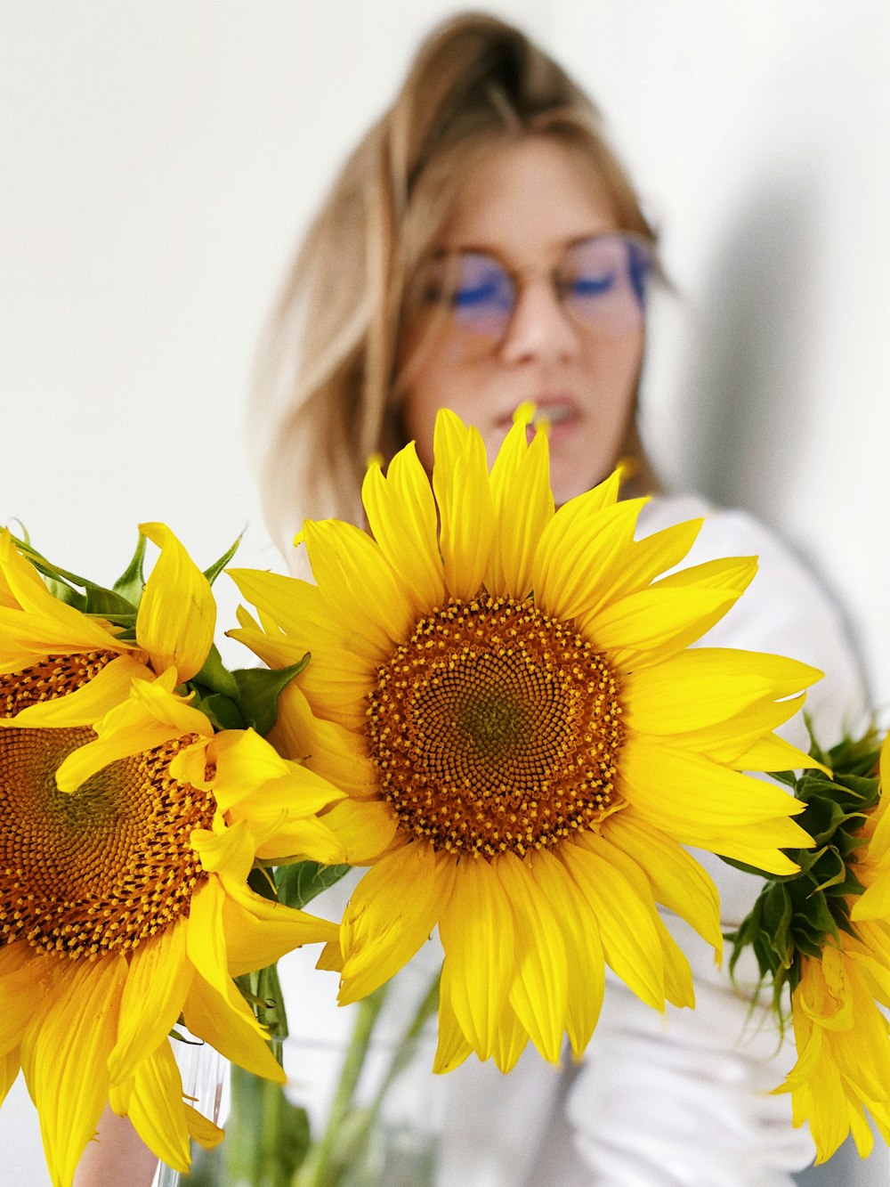 woman in black framed eyeglasses holding sunflower