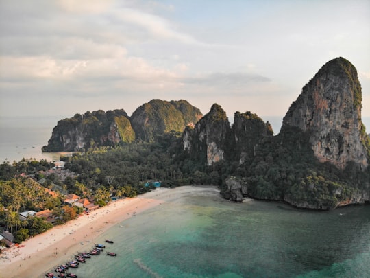 green and brown mountain beside body of water during daytime in Railay Beach Thailand