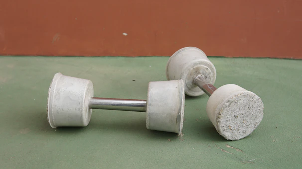 Two identical dumbbells resting on a wooden floor side by side.