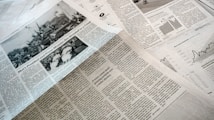 A collection of printed newspapers with articles containing texts, images, and graphs spread out. The layout includes columns of text, black and white photographs, and statistical graphs, conveying information on a flat surface.