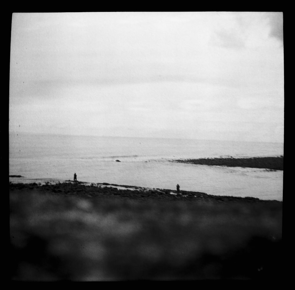 grayscale photo of people walking on beach