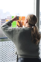 woman in gray sweater holding smartphone
