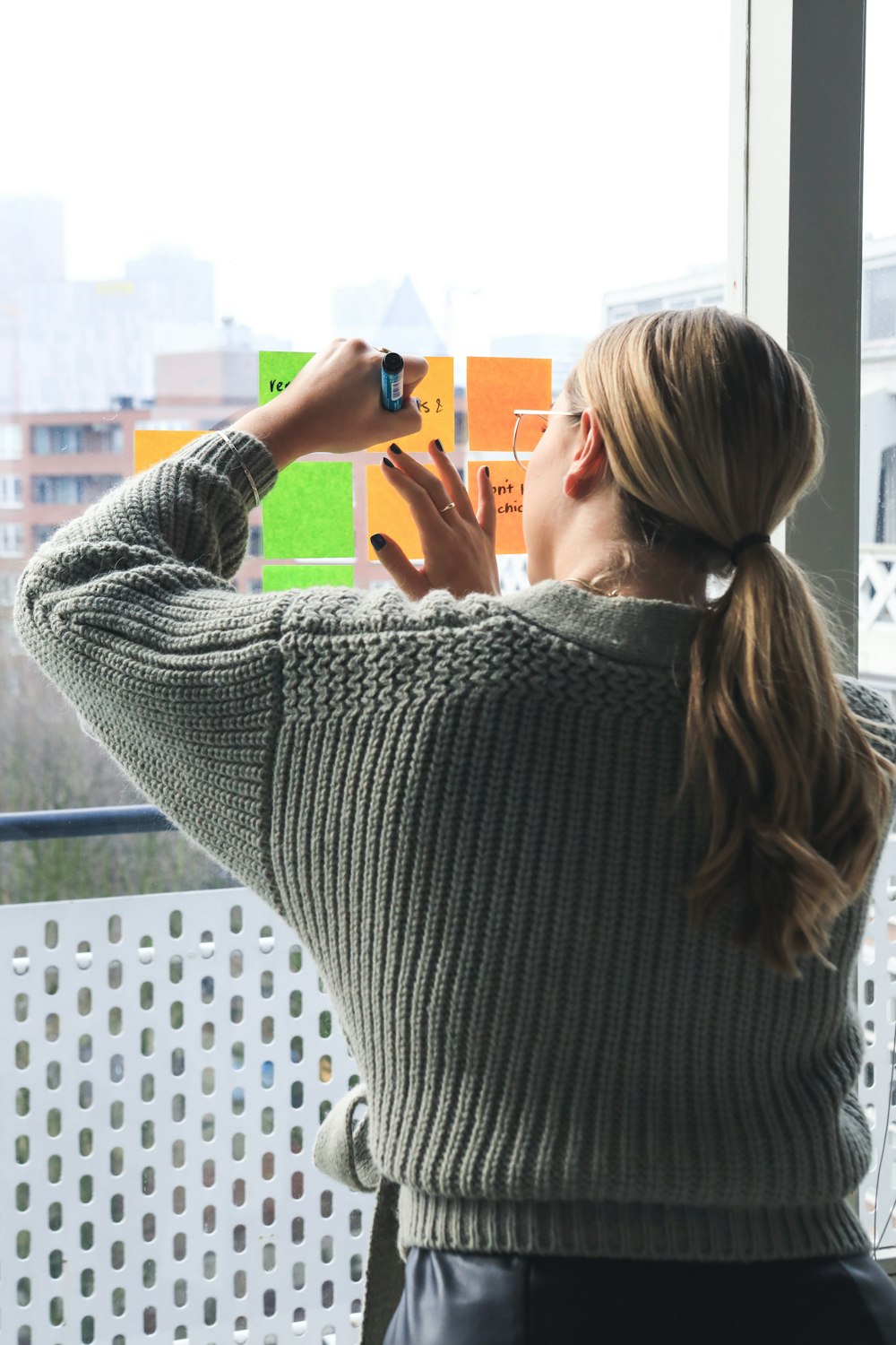 woman in gray sweater holding smartphone