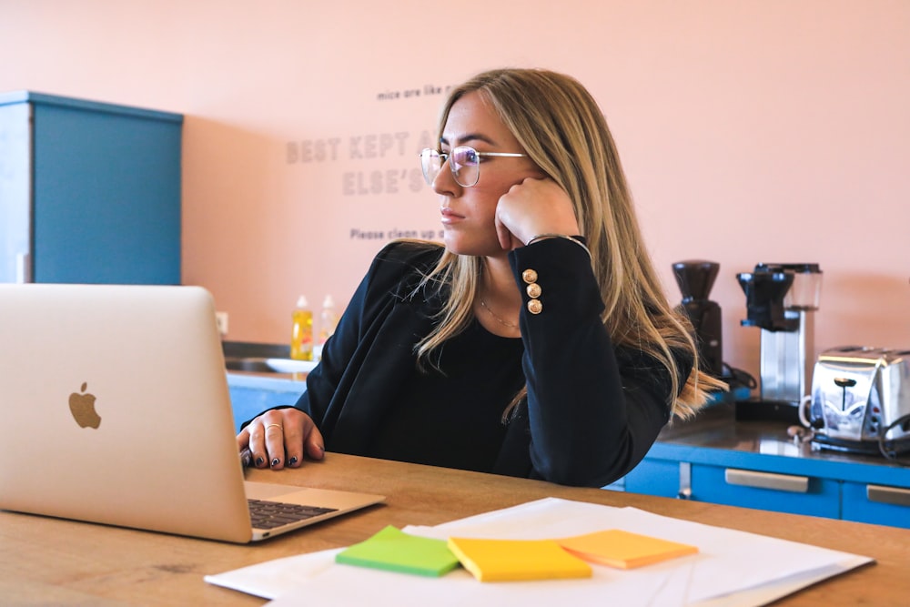 woman in black long sleeve shirt wearing black framed eyeglasses using macbook