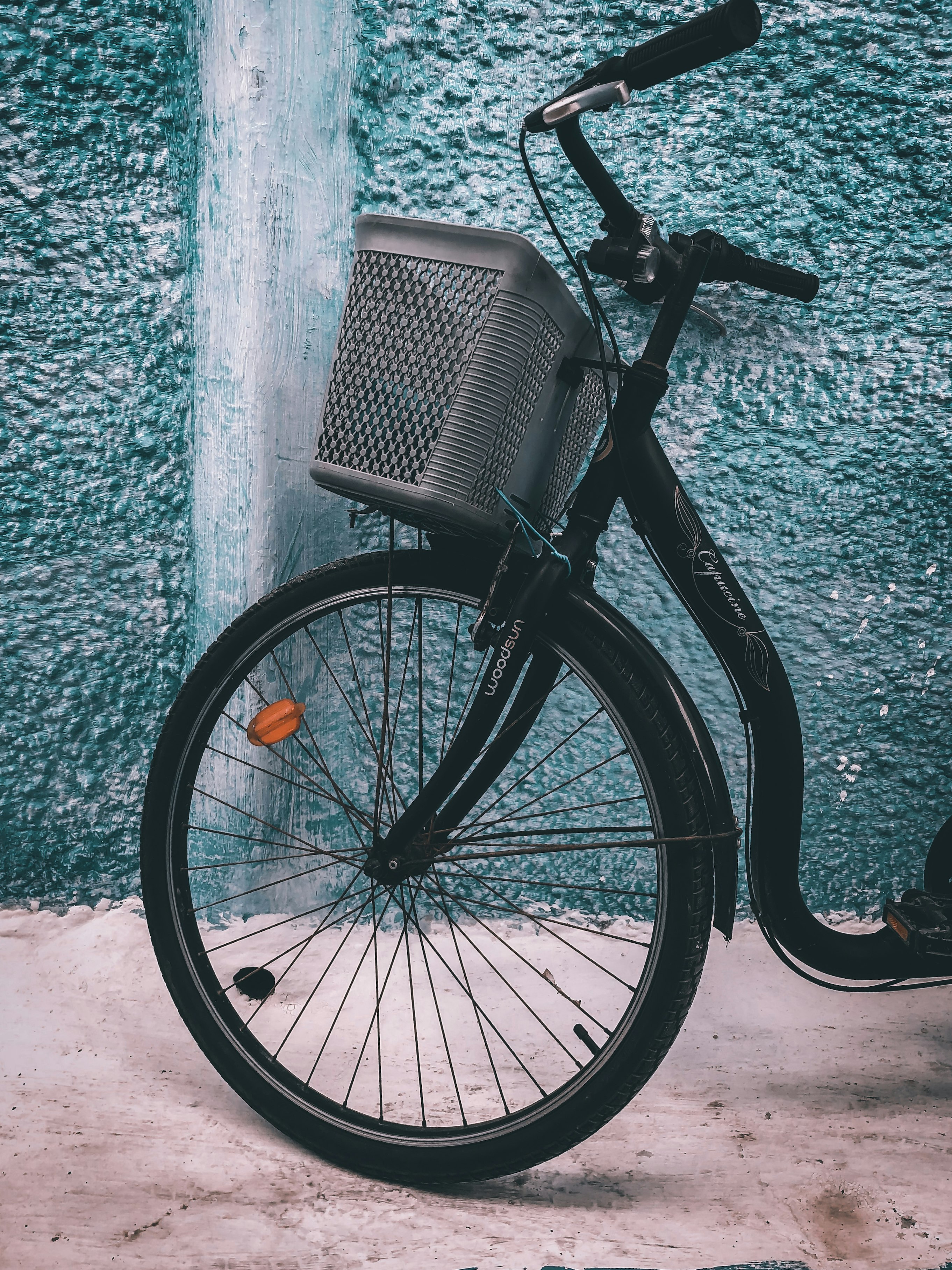 black city bicycle leaning on green concrete wall