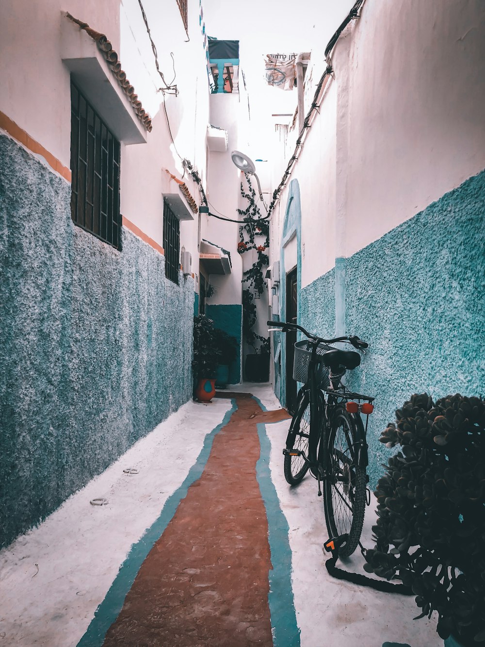 black bicycle parked beside blue concrete wall during daytime