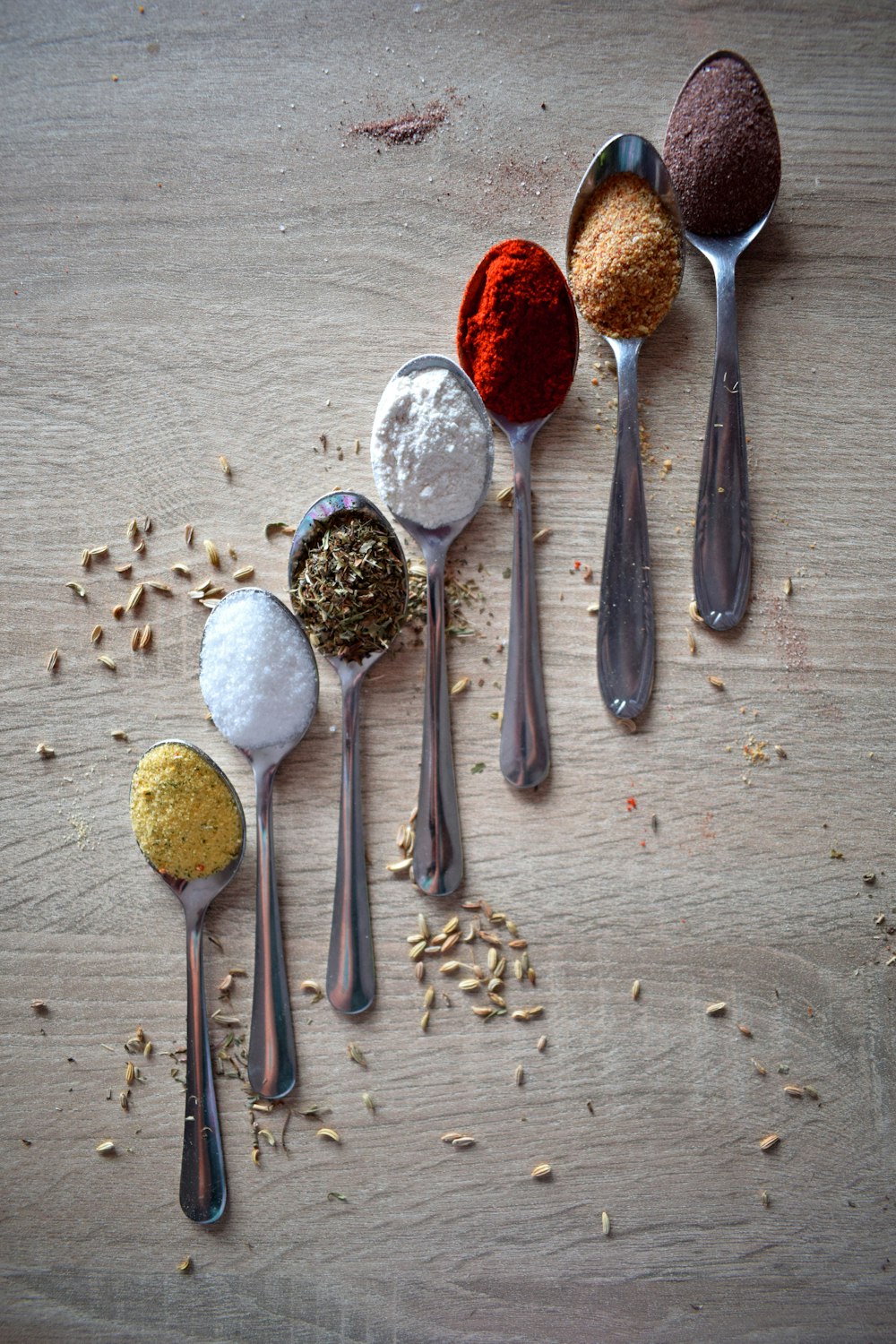 stainless steel spoons and spices on gray wooden table
