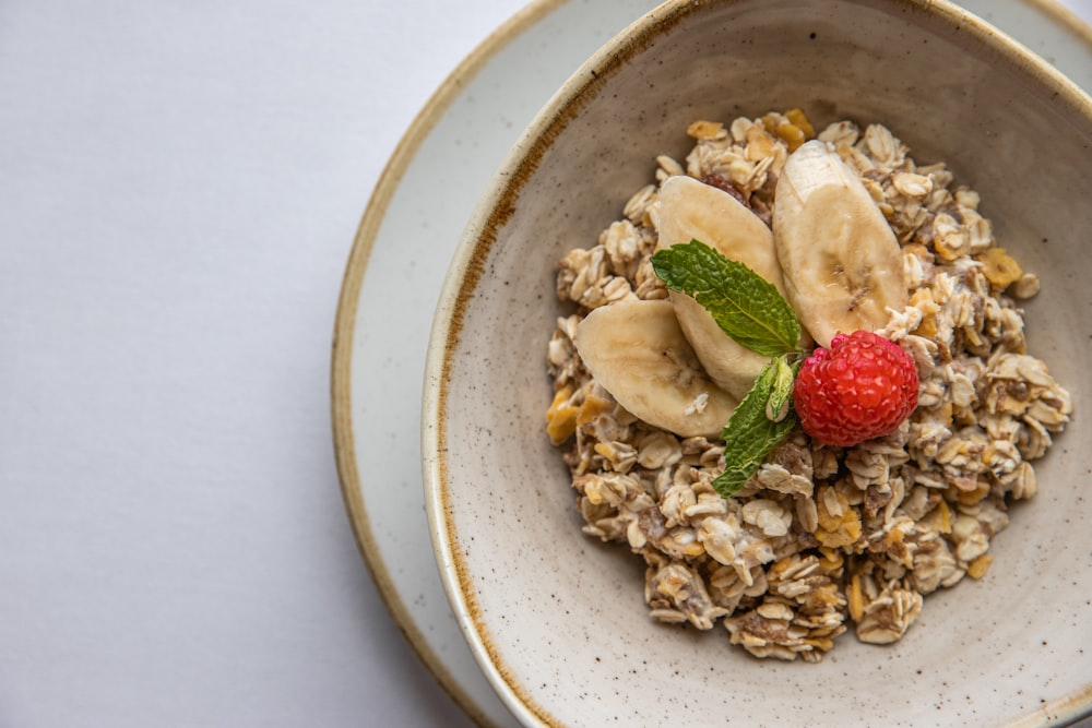 a bowl of granola topped with bananas and a strawberry