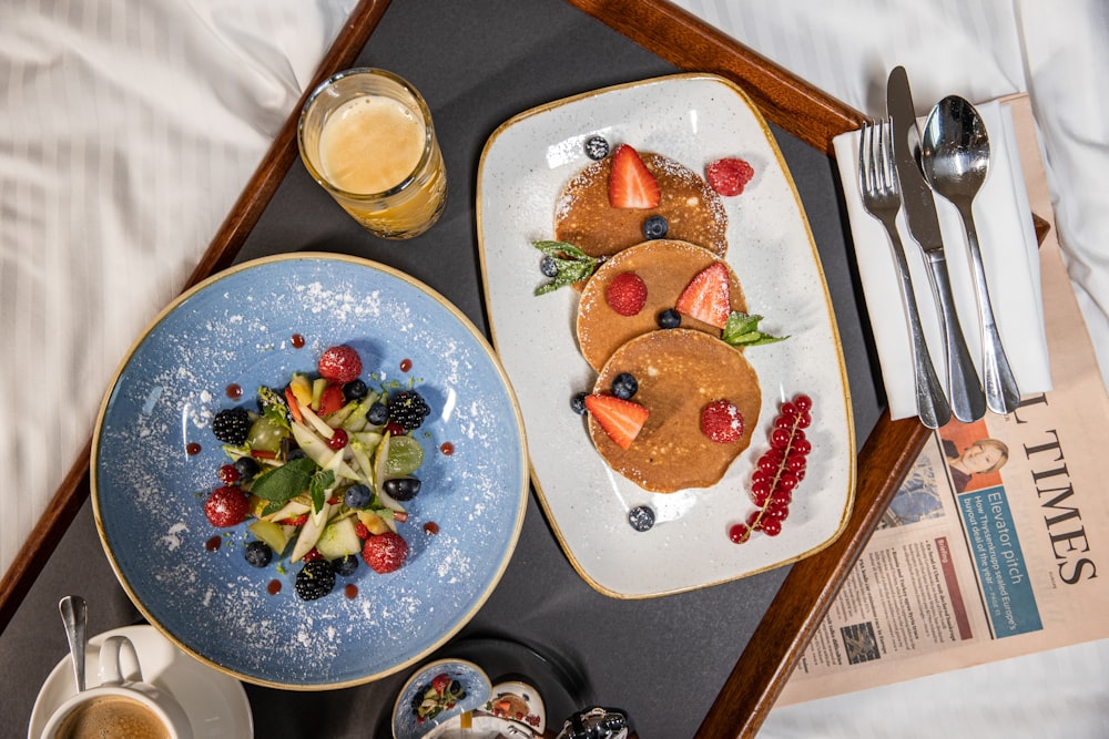 a tray with two plates of food and a glass of orange juice