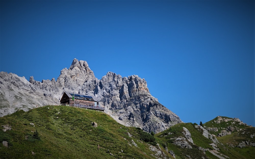 brown house on green grass field near rocky mountain under blue sky during daytime