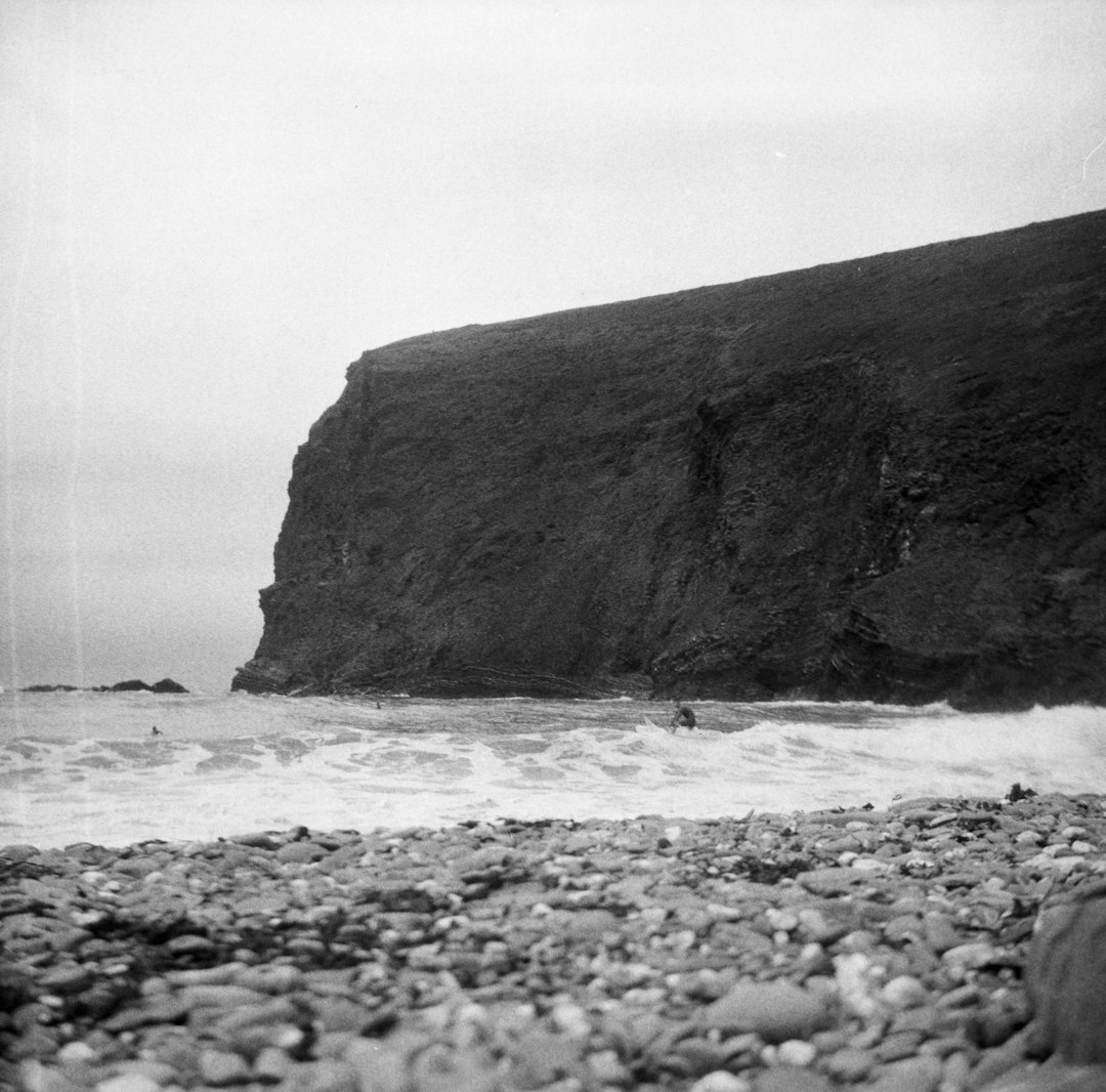 grayscale photo of rock formation on sea