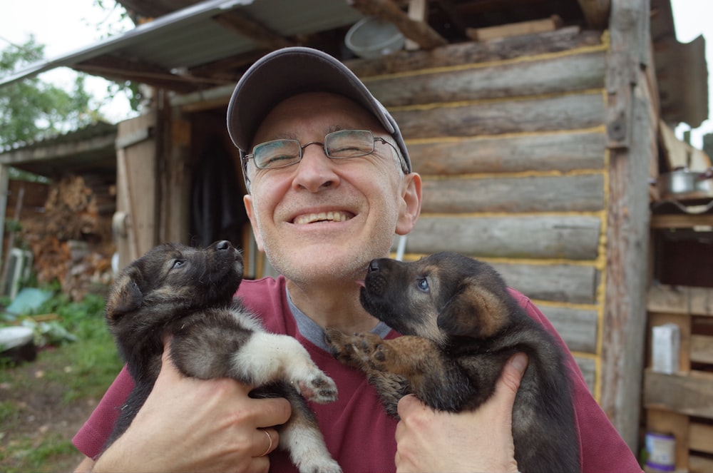 smiling woman holding black and brown short coated dog