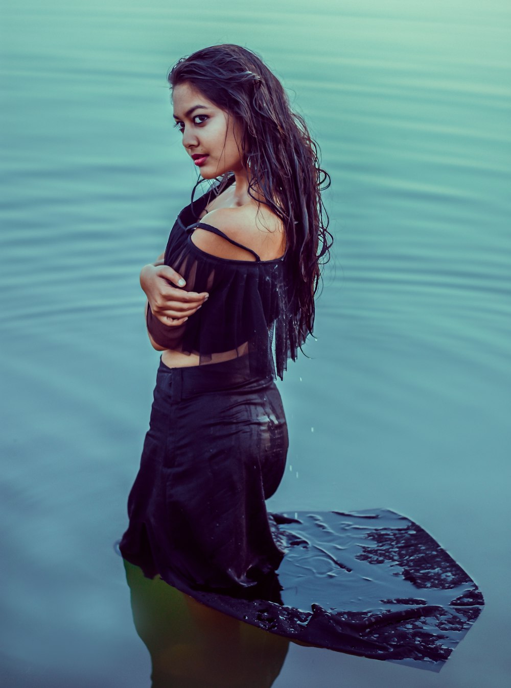 Mujer con camiseta sin mangas negra y pantalones negros de pie sobre el agua