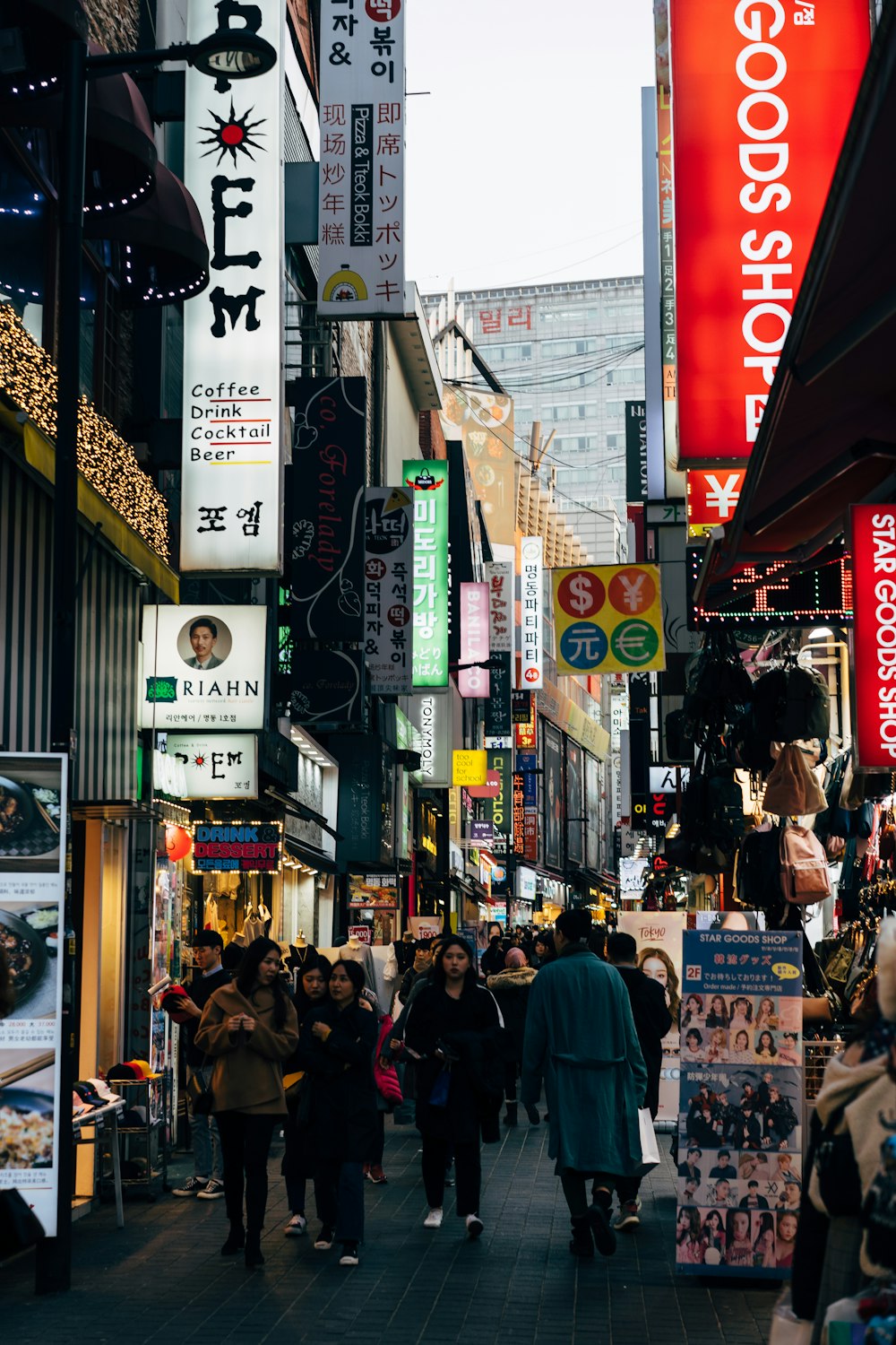 a group of people walking down a street next to tall buildings