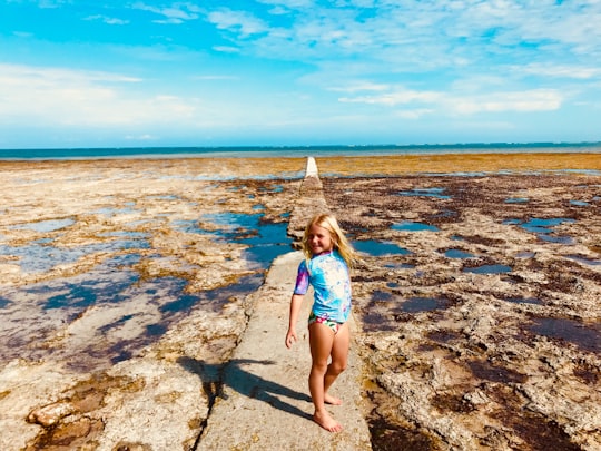 girl in blue and white bikini standing on rocky shore during daytime in Diani Beach Kenya