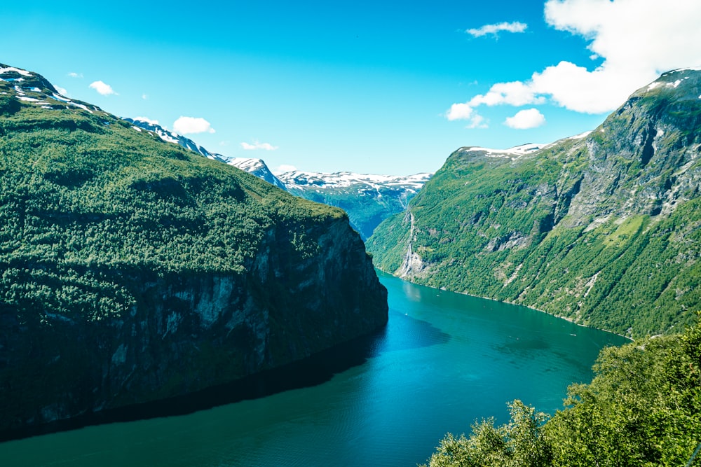 Grüne und schwarze Berge am blauen See unter blauem Himmel tagsüber